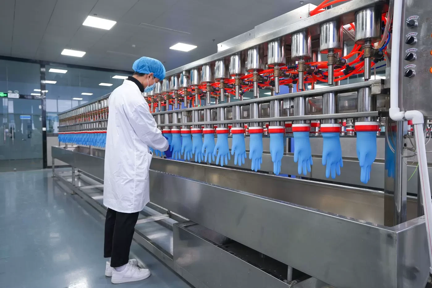Staff working beside inflated blue gloves at an inspection line