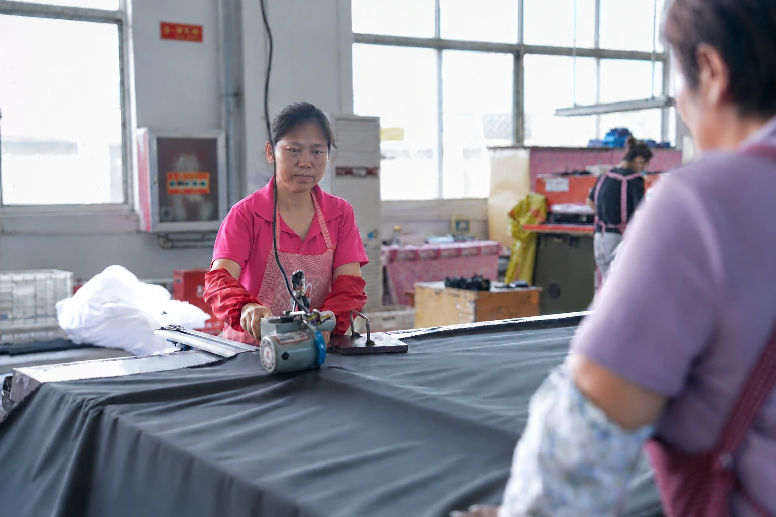 Operator cutting fabric at a factory worktable