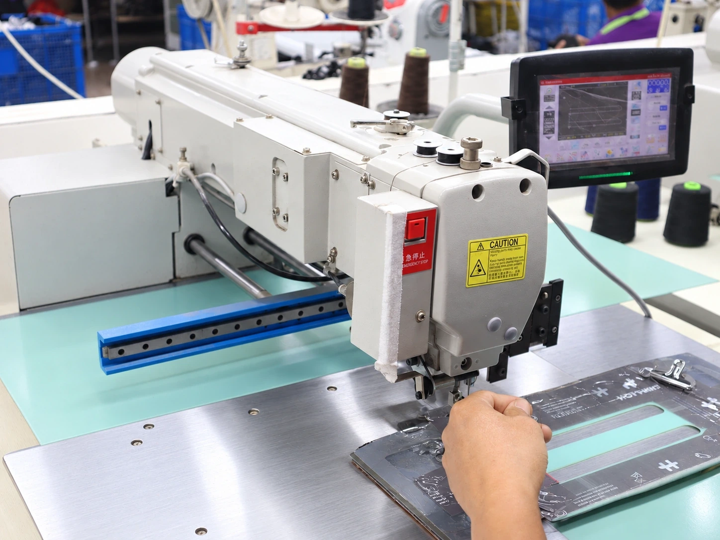 Operator positioning material in a programmable sewing machine