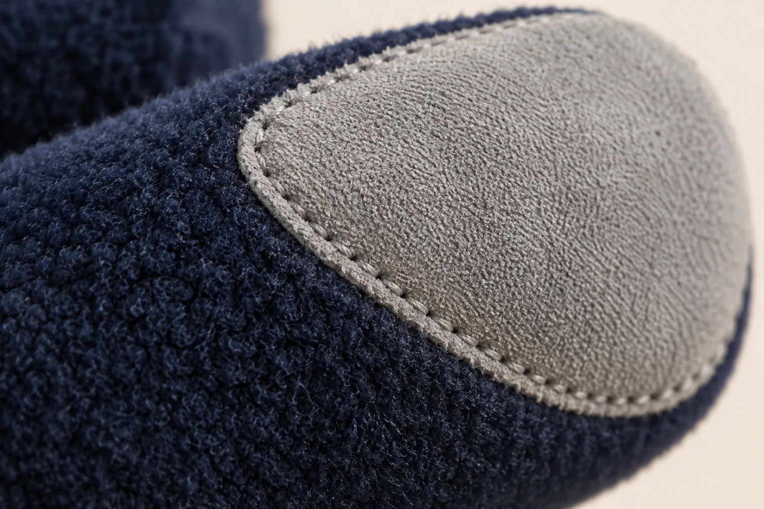 Navy fleece touchscreen glove: extreme macro light gray contact insert sewn onto palm-side of fingertip.