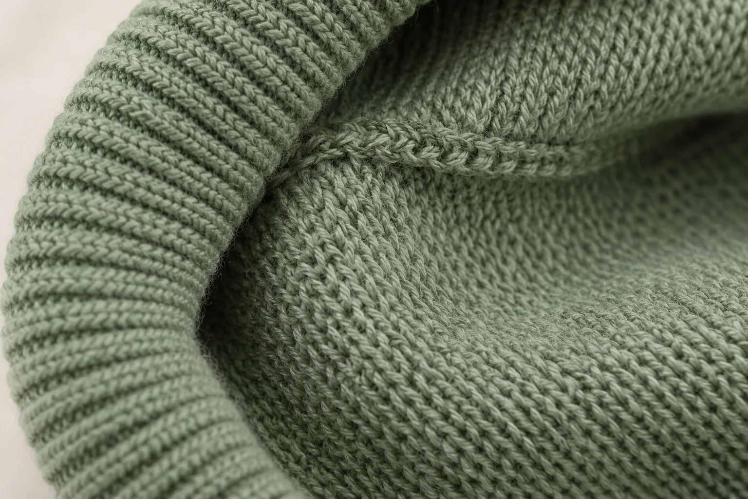 Sage-green glove: macro inside the turned folded cuff, showing reverse purl loops and neat transition to inside palm.