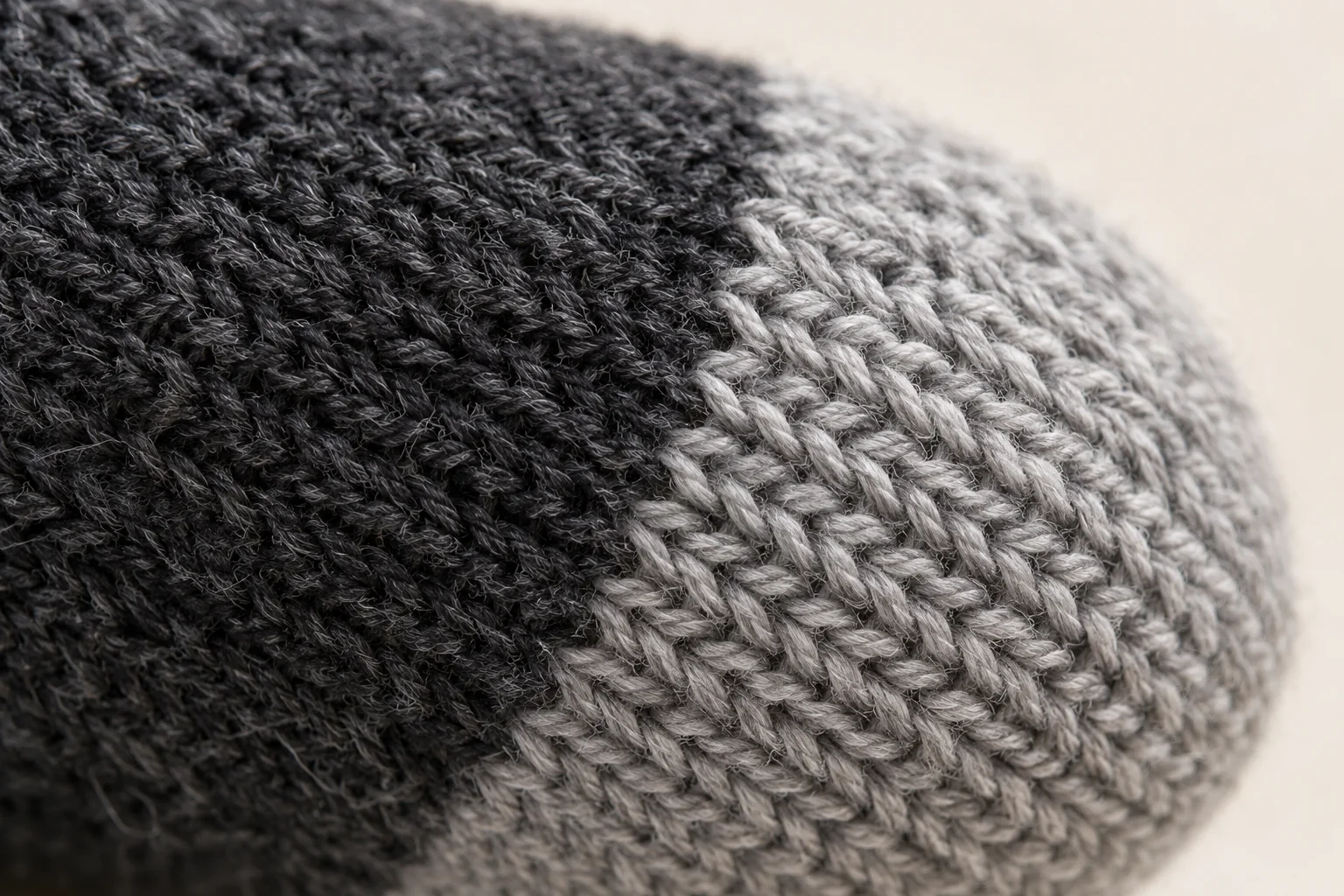 Charcoal knit touchscreen glove: extreme macro of the color boundary between charcoal finger body and light gray knitted contact tip.