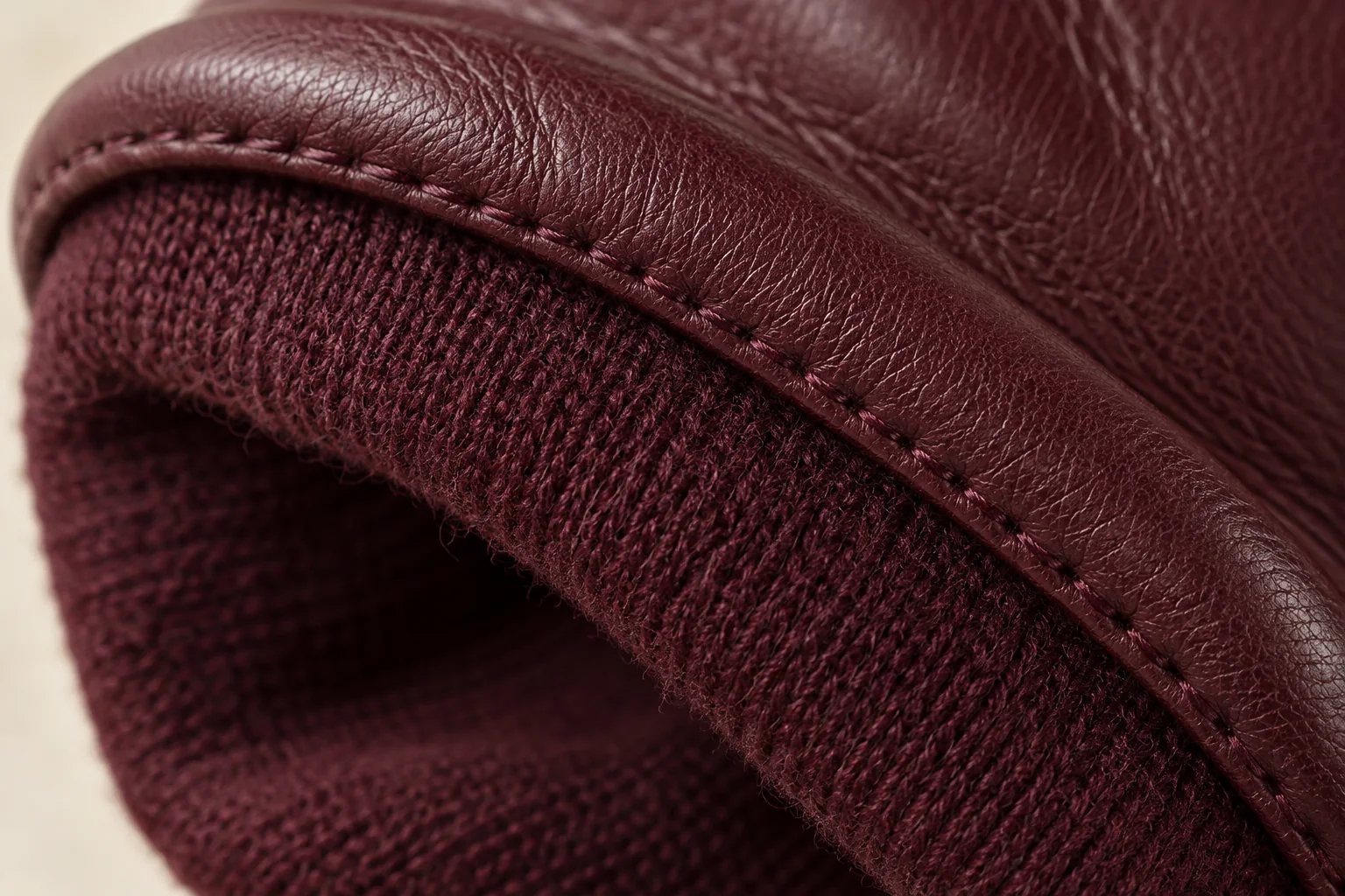 Burgundy leather glove: close macro inner cuff, dark burgundy fine-knit lining attached beneath burgundy turned leather rim.