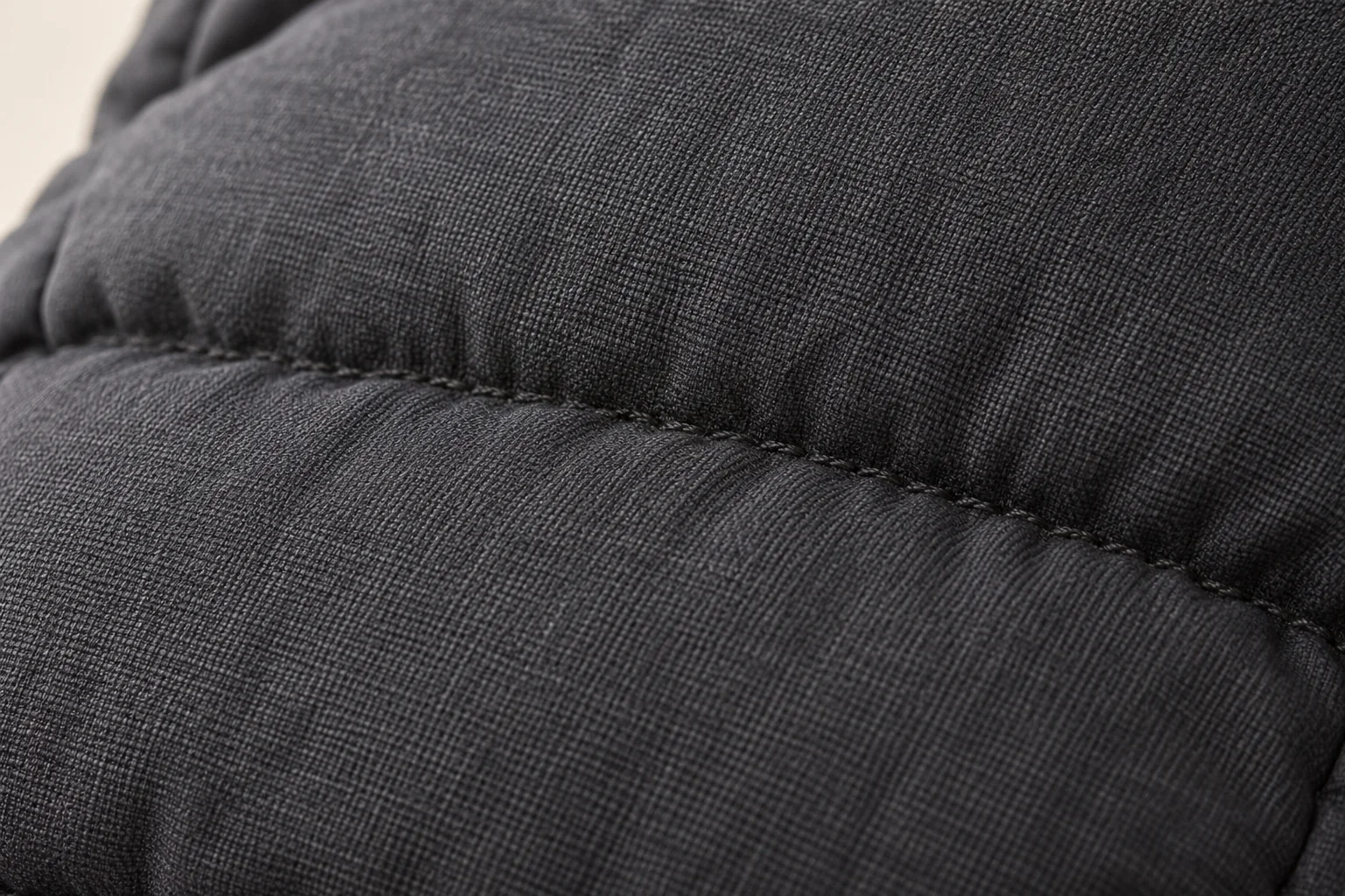 Charcoal winter glove: macro across two adjacent horizontal quilt channels on hand-back shell.