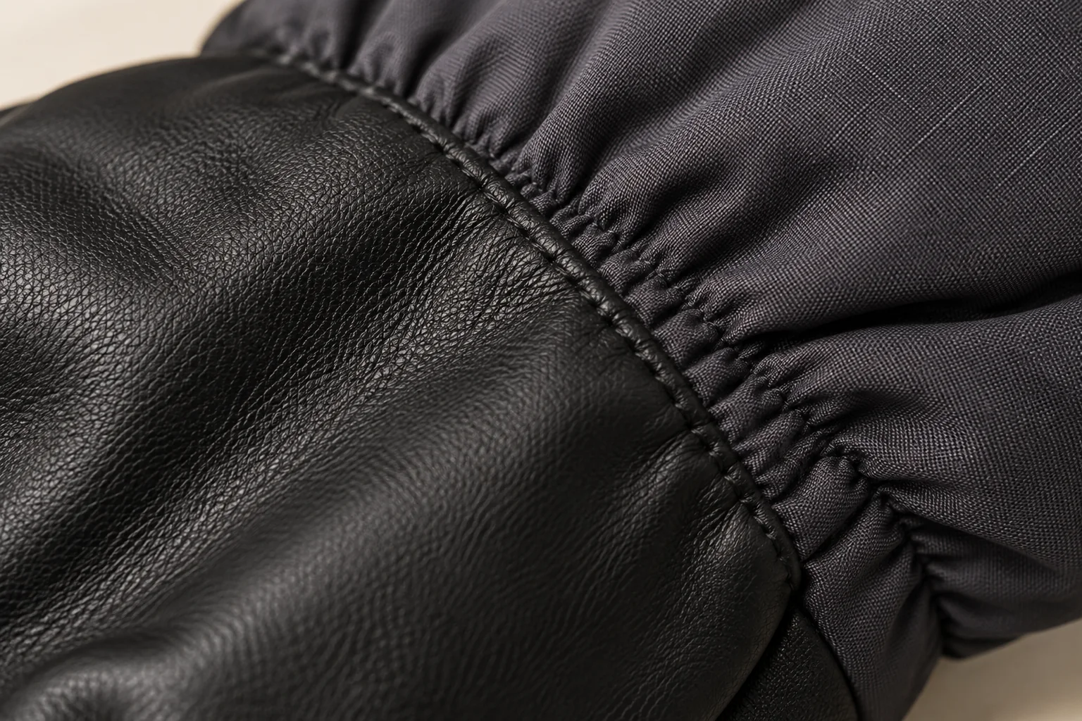 Quilted winter glove: macro black smooth palm panel joining charcoal gathered wrist shell.